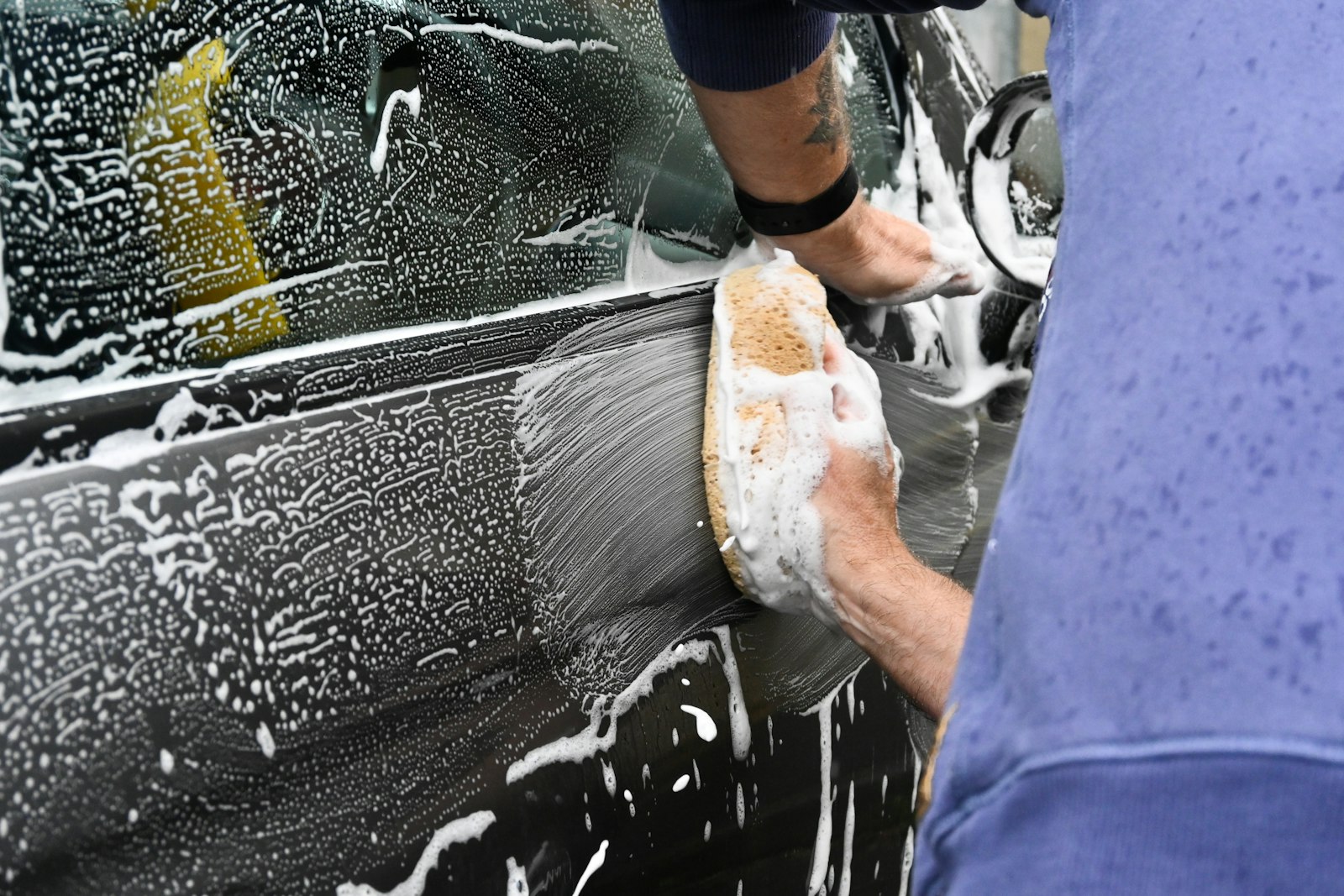 Detailer washing a car by hand with a sponge