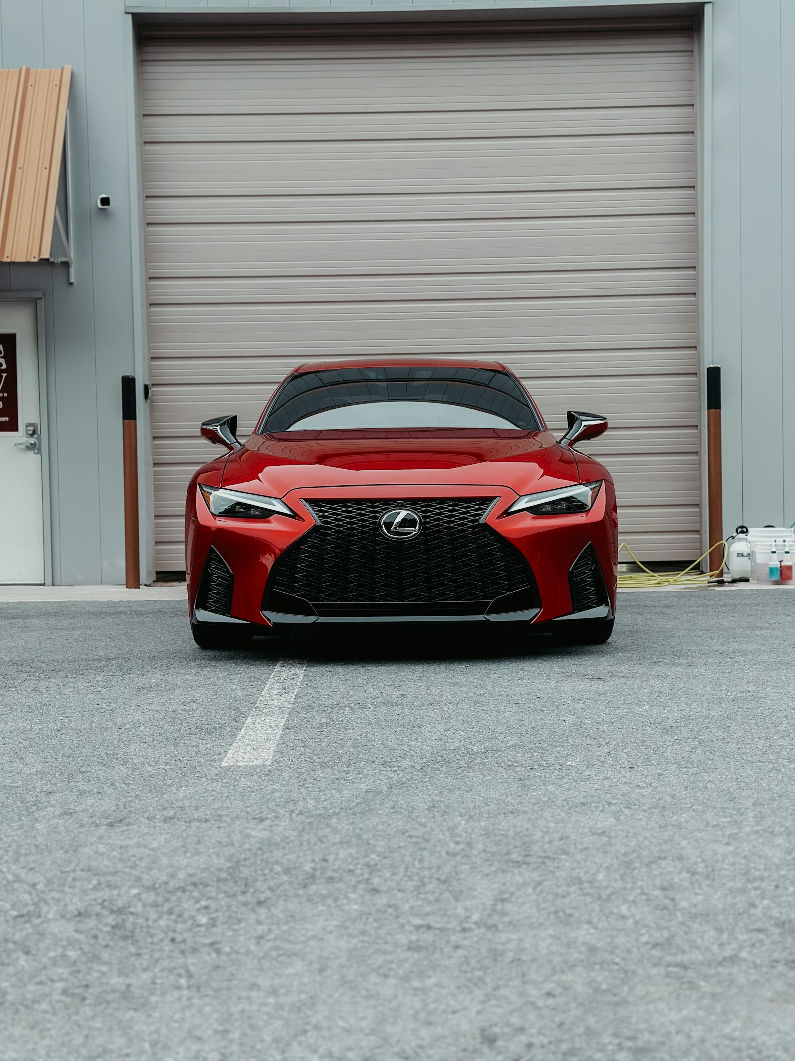 Red sports car parked in front of a garage